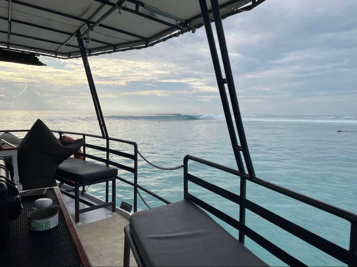 View from the deck of the Mahalo at dawn, an empty wave peeling in the distance